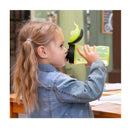 Child drinking from a green Chicco My Tumbler cup with a rim spout, wearing a denim jacket, sitting at a table.