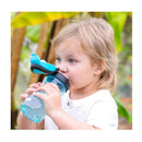 Child drinking from a teal Chicco My Tumbler Rim Spout 12Oz. cup, featuring a spill-proof design, in a lush outdoor setting.