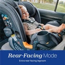 Chicco OneFit LX ClearTex All-in-One Car Seat in rear-facing mode with a smiling baby seated inside, showcasing legroom and safety features.