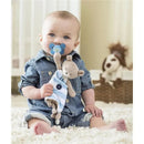 Baby sitting on a soft rug, holding a Chicco Pocket Buddy in blue with a teddy bear attached, and a pacifier in his mouth.