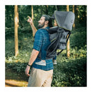 A man carrying a child in a Chicco SmartSupport Backpack Carrier in a woodland setting, pointing at something ahead.