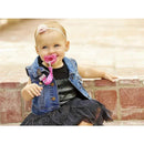 Toddler sitting on a brick surface wearing a denim vest and black skirt, holding a pink Chicco two-in-one pacifier clip.