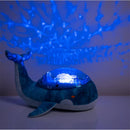 Blue whale-shaped night light projects calming ocean wave patterns. Features a soft plush texture and a serene smiling face.