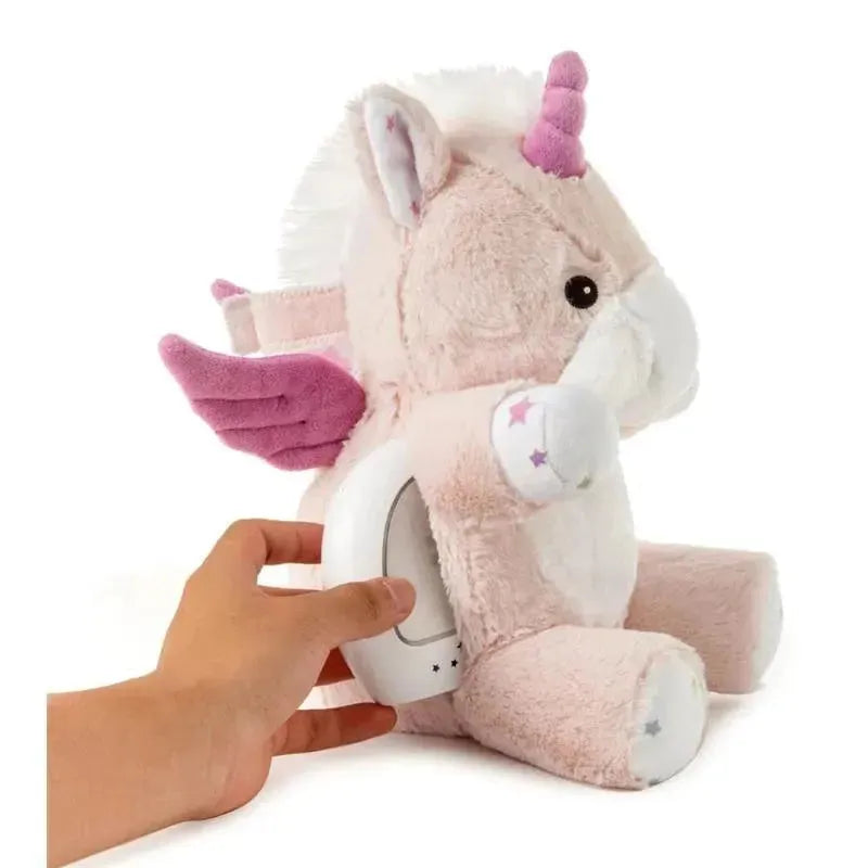 Soft pink unicorn plush toy with wings and a light projector being activated by a hand.
