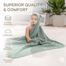 Hooded towel in fern green color, with a baby wrapped in it, showcasing softness and absorbency features.