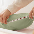 A hand opens a zipped pocket of a green swaddle blanket, showcasing its zipper closure design.