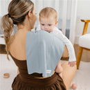 Soft blue burp cloth draped over a woman’s shoulder while holding a baby, showcasing comfort and absorbency.