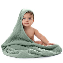 Hooded baby towel in fern green with a seated baby, partially covered, smiling and looking at the camera.