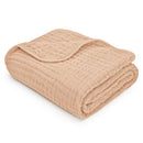 Cream-colored Comfy Cubs muslin baby blanket, featuring a soft, quilted texture, neatly folded.