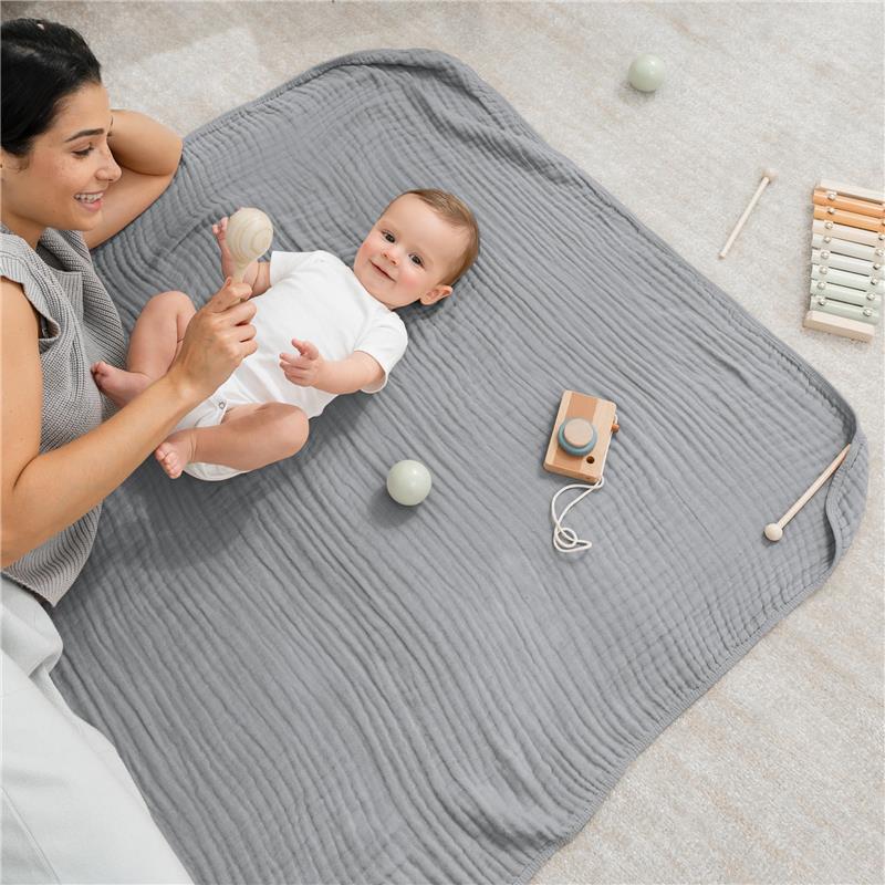 Muslin baby blanket in Heather Blue with a mother and baby playing; includes toys like a rattle and a wooden camera.