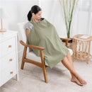 Muslin nursing cover in sage draped over a woman sitting in a chair, providing modesty while nursing.