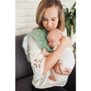 A woman holds a sleeping baby while wearing a green burp cloth with letters, showcasing the Copper Pearl burp cloth set.