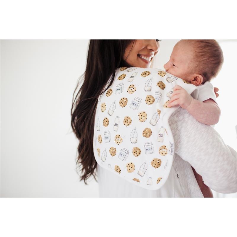 Premium baby burp cloth featuring a playful milk and cookie print, held by a smiling woman with a baby in her arms.