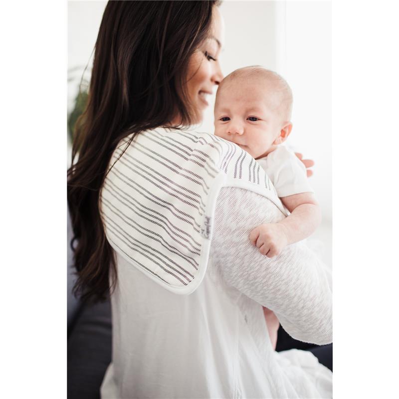 A smiling woman holds a baby on her shoulder, wearing a striped Copper Pearl burp cloth.