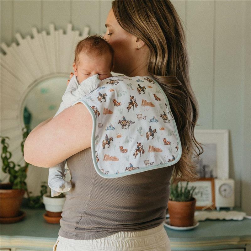 Premium baby burp cloths featuring a colorful goosie pattern, draped over a woman holding a baby.