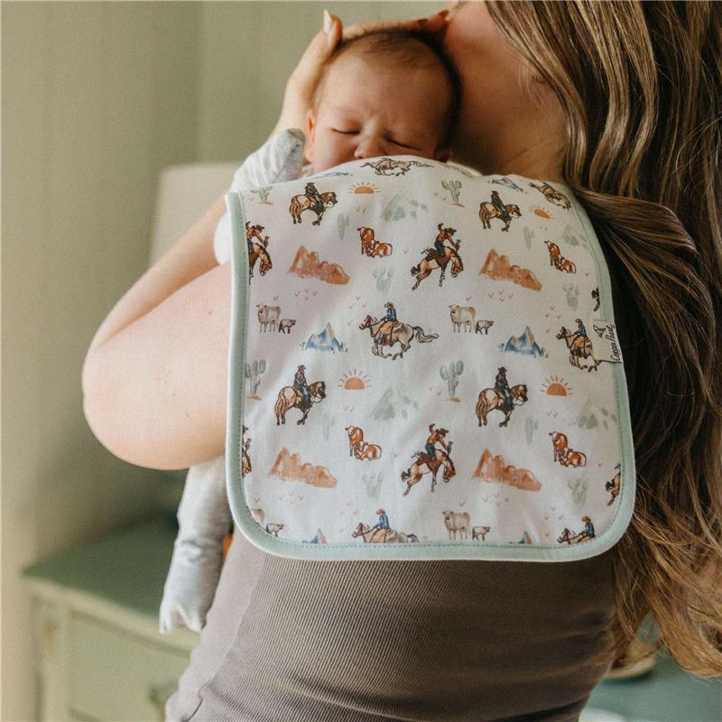 Premium baby burp cloth featuring a cowboy and horse design, draped over a mother holding a baby on her shoulder.