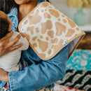 Premium baby burp cloth with a tan and white animal print design, held by a caregiver with an infant.