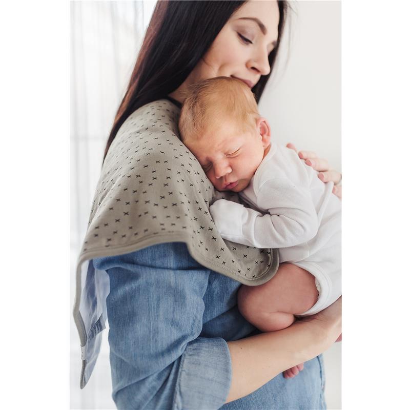 A woman holds a sleeping baby over her shoulder, with a soft, patterned burp cloth draped across her shoulder.