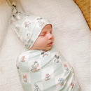 Baby wrapped in a Disney-themed swaddle featuring Mickey Mouse and friends, wearing a matching top knot hat.