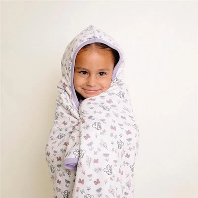 Big kid wearing a Disney Minnie Mouse-themed hooded towel with floral and butterfly patterns, smiling at the camera.