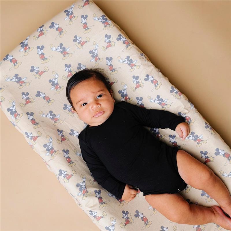Premium diaper changing pad cover featuring Mickey Mouse pattern, with a baby in a black onesie resting on it.