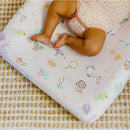 Premium diaper changing pad cover featuring whimsical, colorful illustrations and a baby in a polka dot onesie.