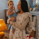 A woman holds a young child in a cozy room, draped with a playful, Winnie the Pooh-themed quilt blanket.