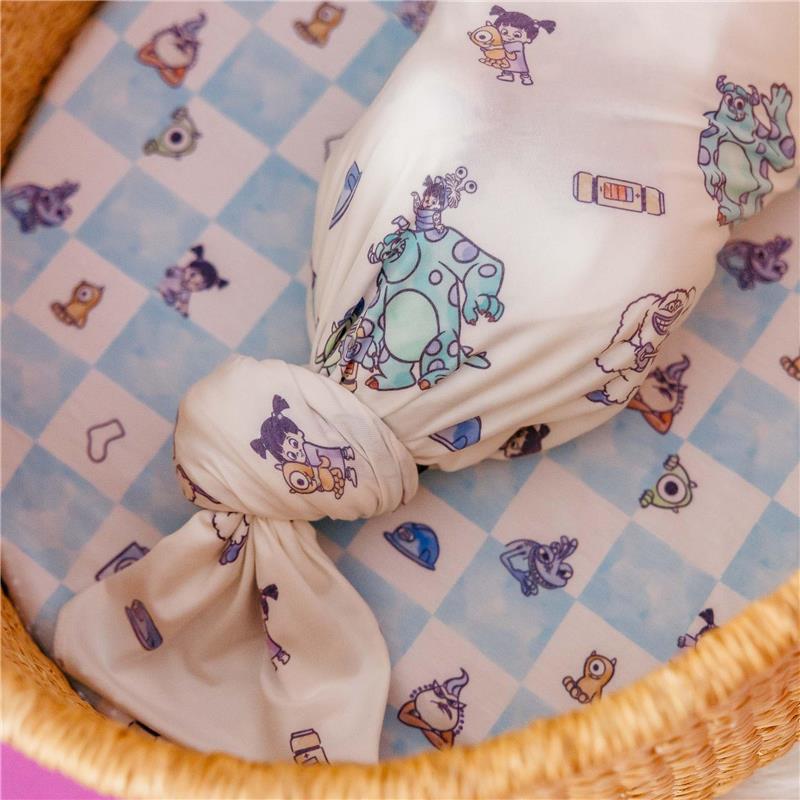 Knit blanket featuring Monsters Inc characters, wrapped and displayed on a patterned surface in a basket.