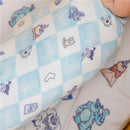 Knit blanket featuring a colorful Monsters Inc. pattern with characters on a light blue and white checkered background.