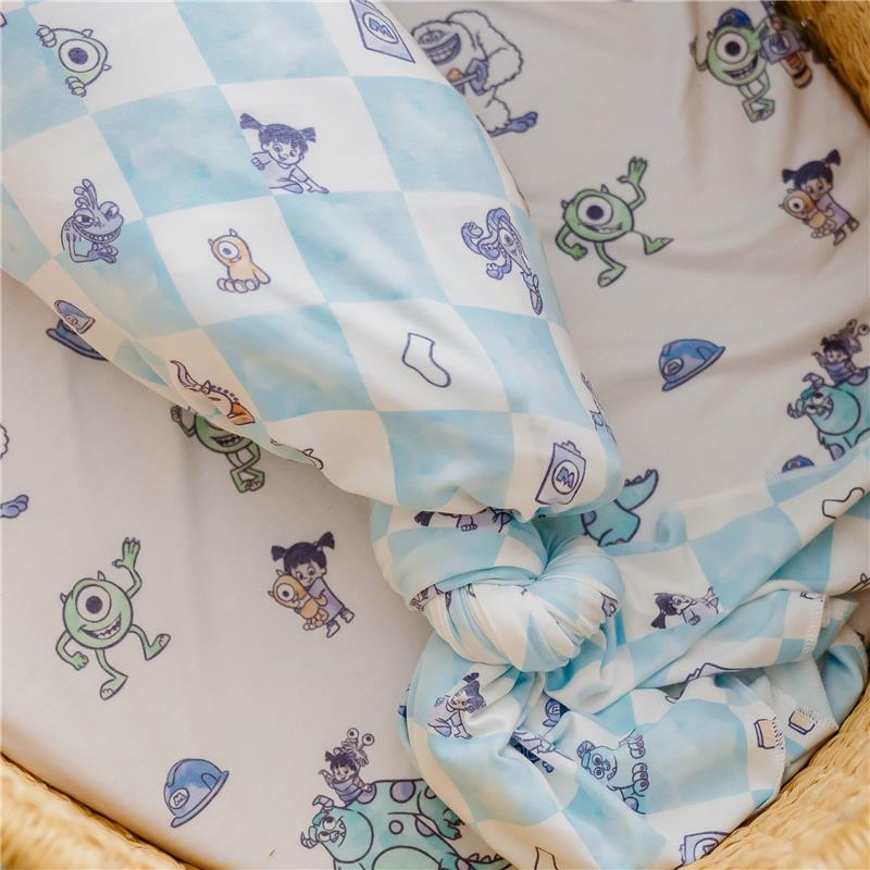 Knit blanket featuring characters from Monsters Inc, with a blue checkered pattern and playful illustrations.