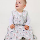 A toddler in a Mickey Mouse-themed sleep bag sits on the floor, looking up with curiosity.