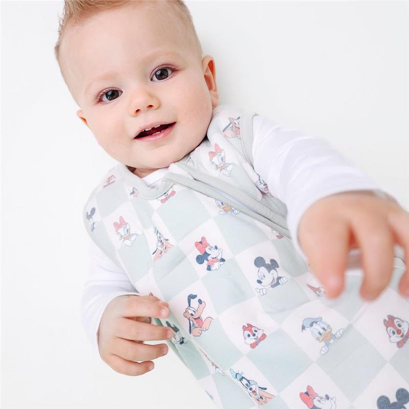 A happy baby wearing a Copper Pearl 3-layer knit sleep bag featuring Mickey Mouse and friends, reaching out with one hand.