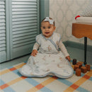Baby wearing a Copper Pearl Premium 3-Layer Knit Sleep Bag featuring Winnie the Pooh characters, sitting on a colorful rug.