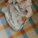 Premium 3-layer knit sleep bag featuring Winnie the Pooh and friends, worn by a baby on a colorful woven rug.