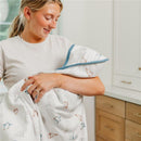 Woman holding a Copper Pearl Premium Baby Knit Hooded Towel with a whimsical animal print, smiling softly.