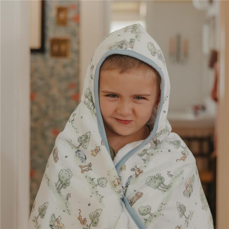 Big kid wearing a hooded towel featuring Hundred Acre Wood characters, smiling confidently.