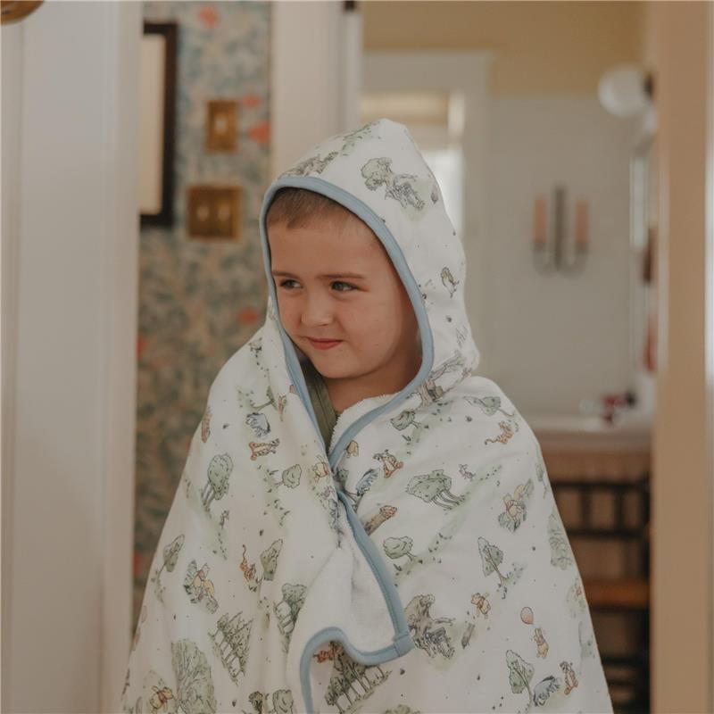 Big kid hooded towel featuring Hundred Acre Wood characters, draped around a smiling child in a cozy indoor setting.