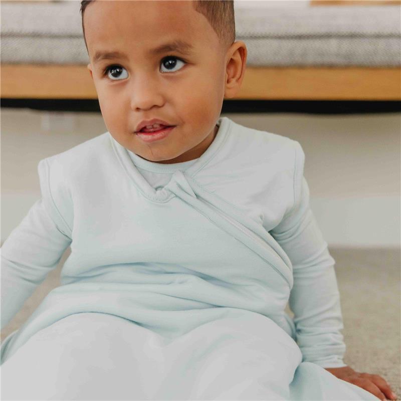 Child wearing a light blue Copper Pearl 0.5 Tog Sleep Bag, looking up with a curious expression.