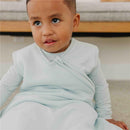Child wearing a light blue Copper Pearl 0.5 Tog Sleep Bag, looking up with a curious expression.
