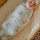 Knit blanket featuring Winnie The Pooh and friends, swaddling a baby, showcasing soft pastel colors and playful designs.