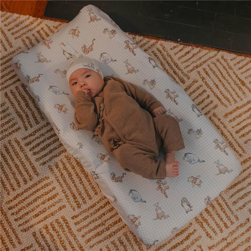 Premium diaper changing pad cover featuring Winnie The Pooh and friends, with a baby peacefully lying on it.