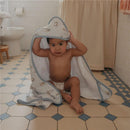 Baby sitting on a bathroom floor, wearing a diaper and holding a Copper Pearl Winnie the Pooh hooded towel over their head.