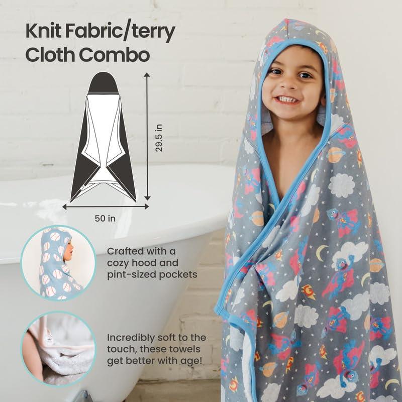 A smiling child wearing a Copper Pearl Wizarding World™ hooded towel with colorful illustrations, showcasing its cozy hood and soft fabric.