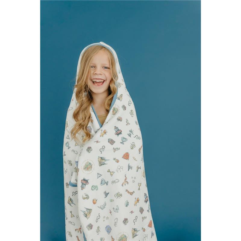 Big kid wearing a whimsical hooded towel featuring various magical designs, smiling against a blue background.