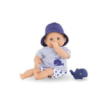 Soft-body 12-inch baby doll in blue striped outfit and purple hat, sitting next to a rubber whale toy.