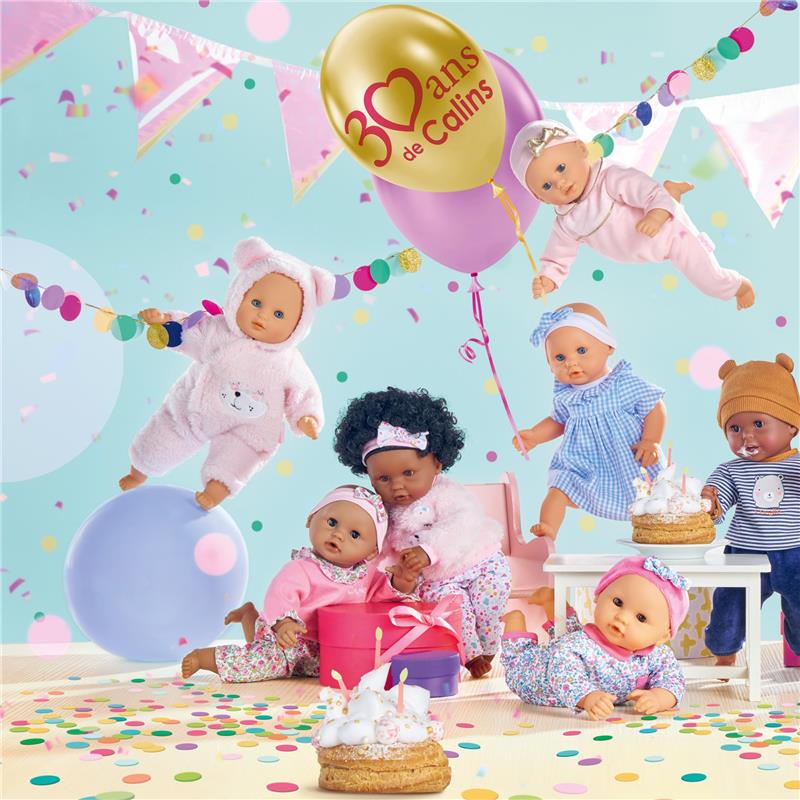 Bébé Calin Capucine dolls celebrate with confetti, balloons, and birthday cake in a playful, festive setting.