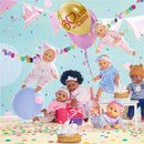 Bébé Calin Capucine dolls celebrate with confetti, balloons, and birthday cake in a playful, festive setting.