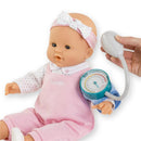 Corolle doll dressed in pink overalls with a stethoscope on its arm, being checked for blood pressure.