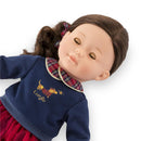 Corolle Dolls Ma Perle doll wearing a navy sweater with a plaid collar and a gold embroidered dog design.