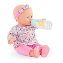 Magic Milk Baby Doll with floral outfit and pink headband, drinking from a baby bottle with a cartoon character.